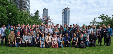 100+ people gathered for a group photo on the grounds of the library at the Dock